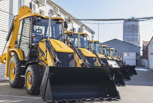 Equipment Rental Insurance - Row of Construction Equipment Displayed for Rental Use Behind a Warehouse on a Sunny Day