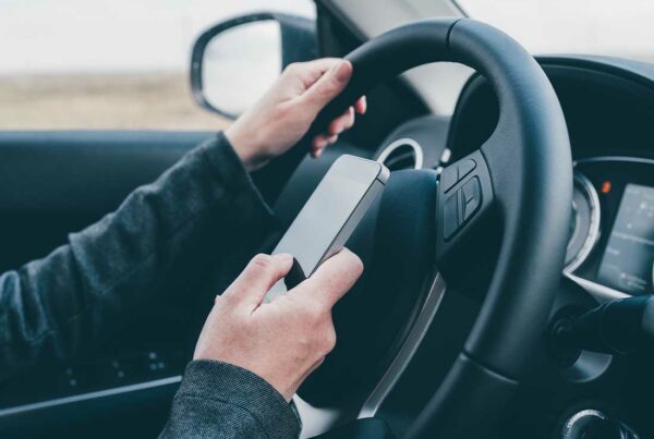 SR-22 - Close-up of a Reckless Driver Texting While behind the Wheel of a Moving Vehicle